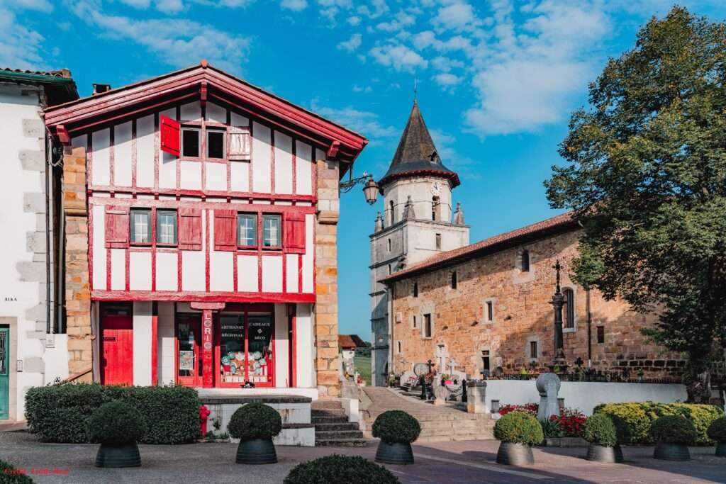 Maison traditionnelle basque à colombages rouges et église Notre-Dame de l’Assomption à Ainhoa, Pays Basque.