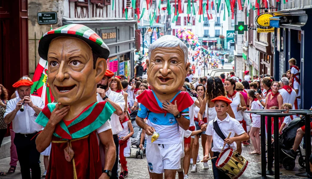 Fête traditionnelle du Pays basque avec danseurs, musiciens et participants dans les rues d'un village.
