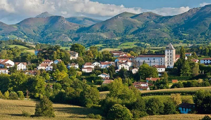 Village traditionnel du Pays basque avec ses maisons blanches aux volets rouges et son environnement naturel.